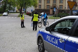 Zdjęcie kolorowe. Policjanci rozmawiają z zatrzymanymi do kontroli rowerzystami