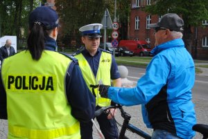 Zdjęcie kolorowe. Policjanci rozmawiają z zatrzymanymi do kontroli rowerzystami