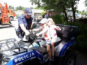 Zdjęcie kolorowe. Policjant pokazuje dzieciom quada
