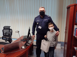 Zdjęcie kolorowe. Chłopiec wspólnie z Komendantem Powiatowym Policji w Szczecinku pozuje do zdjęcia