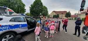 Zdjęcie kolorowe. Dzień dziecka w Łubowie. Dzieci zebrały się wokół policyjnego radiowozu