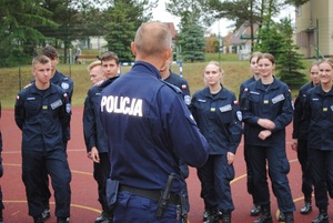 Zdjęcie kolorowe. Uczniowie ćwiczą policyjną musztrę.
