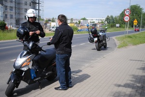 Zdjęcie kolorowe. Policjant na motocyklu patroluje ulice.