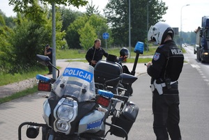 Zdjęcie kolorowe. Policjant na motocyklu patroluje ulice.