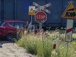 Zdjęcie kolorowe. Czerwony samochód na tle pociągu towarowego