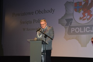 Zdjęcie kolorowe. Komendant Powiatowy Policji w Szczecinku podczas przemówienia na scenie