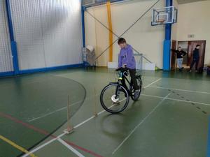 Zdjęcie kolorowe. Uczeń na rowerze pokonuje tor przeszkód