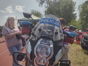 Zdjęcie kolorowe. Kobieta siedząca za kierownicą policyjnego motocyklu
