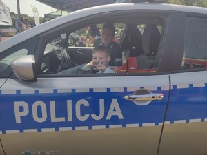 Zdjęcie kolorowe. Dzieci siedzą w policyjnym samochodzie