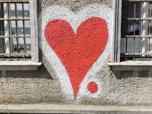 Zdjęcie kolorowe. Czerwone serce z białą otoczką namalowane na murze