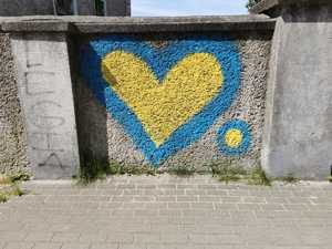 Zdjęcie kolorowe. Żółte serce z niebieską obwódką namalowane na murze