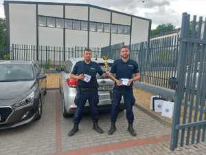 Zdjęcie kolorowe. Policjanci ze Szczecinka trzymający puchar za zajęcie 2 miejsca