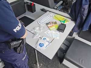 Zdjęcie kolorowe. Na stoliku w policyjnym busie wyłożone są elementy odblaskowe i materiały promocyjne z zakresu bezpieczeństwa na drodze
