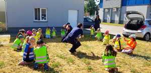 Zdjęcie kolorowe. Policjanci razem z dziećmi ćwiczą postawę bezpieczną w kontakcie z agresywnym psem tzw &quot;żółwia&quot;