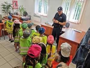 Zdjęcie kolorowe. Policjant rozmawia z dziećmi