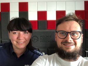 Zdjęcie kolorowe. Zdjęcie policjantki i dziennikarza prowadzącego rozmowę. Zdjęcie na tle na którym widać napis Polskie Radio Koszalin