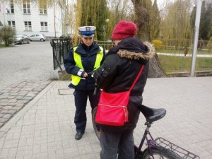 Policjantka wręcza zatrzymanej do kontroli rowerzystce odblask.