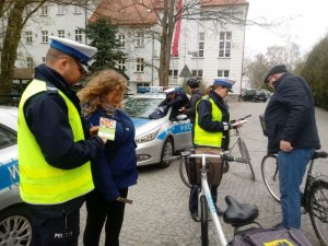 Na zdjęciu widać dwóch policjantów i dwóch rowerzystów, którzy otrzymują Poradniki Rowerzysty od mundurowych