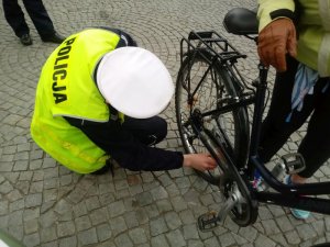 Policjant montuje światełka odblaskowe w rowerowym kole