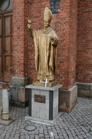 Zdjęcie kolorowe. Na zdjęciu pomnik Jana Pawła II bez pastorału z krzyżem.