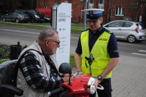 Zdjęcie kolorowe. Policjanci rozmawiają z zatrzymanymi do kontroli rowerzystami