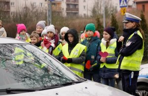 Zdjęcie kolorowe. Policjantka w obecności dzieci prowadzi działania na drodze