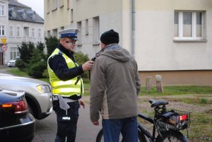 Zdjęcie kolorowe. Policjant bada trzeźwość rowerzysty