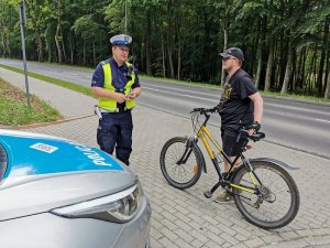 Zdjęcie kolorowe. Policjant bada trzeźwość rowerzysty