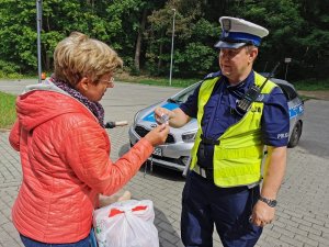 Zdjęcie kolorowe. Policjant bada trzeźwość rowerzysty