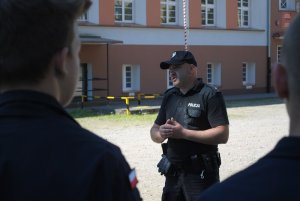 Zdjęcie kolorowe. Policjant prowadzi spotkanie z uczniami klas policyjnych