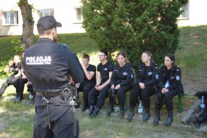 Zdjęcie kolorowe. Policjant prowadzi zajęcia z klasą mundurową