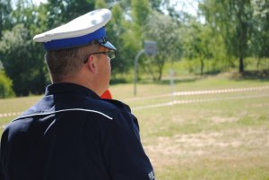 Zdjęcie kolorowe. Policjant śledzi tor jazdy rowerzysty.