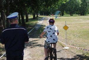 Zdjęcie kolorowe. Policjant śledzi jazdę rowerzysty.