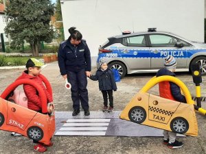 Zdjęcie kolorowe. Policjantka prowadzi zajęcia z przedszkolakami z wykorzystaniem piankowego miasteczka ruchu drogowego