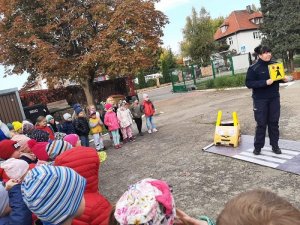 Zdjęcie kolorowe. Policjantka prowadzi zajęcia z przedszkolakami z wykorzystaniem piankowego miasteczka ruchu drogowego