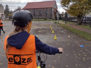 Zdjęcie kolorowe. Uczeń na rowerze porusza się po torze.