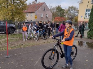 Zdjęcie kolorowe. Uczeń na rowerze porusza się po torze.