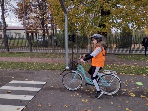 Zdjęcie kolorowe. Uczeń na rowerze porusza się po torze.