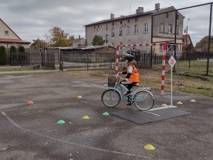 Zdjęcie kolorowe. Uczeń na rowerze porusza się po torze.