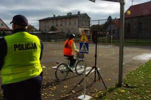 Zdjęcie kolorowe. Uczeń na rowerze porusza się po torze.