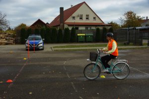 Zdjęcie kolorowe. Uczeń na rowerze porusza się po torze.