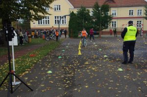 Zdjęcie kolorowe. Uczeń na rowerze porusza się po torze.