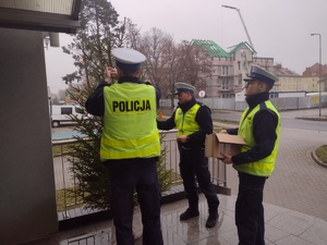 Zdjęcie kolorowe. Policjanci ubierają choinkę w elementy odblaskowe.