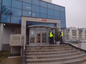 Zdjęcie kolorowe. Policjanci ubierają choinkę w elementy odblaskowe.