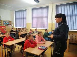 Zdjęcie kolorowe. Spotkanie policjantki z uczniami w klasie