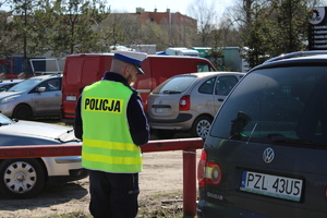 Zdjęcie kolorowe. Policjant dokonuje kontroli pojazdu