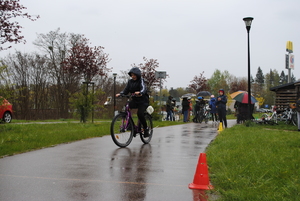 Zdjęcie kolorowe. Uczestnicy na rowerach pokonują slalom.