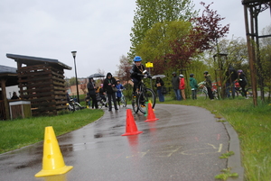 Zdjęcie kolorowe. Uczestnicy na rowerach pokonują slalom.