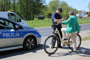 Zdjęcie kolorowe. Policjant rozmawia z rowerzystką