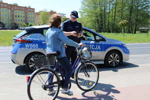 Zdjęcie kolorowe. Policjant rozmawia z rowerzystką